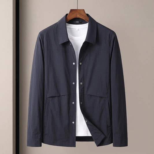 Crease Free Jacket in navy, a lightweight woven shirt jacket with a pointed collar, metal snap placket and welt hip pockets on a wooden hanger