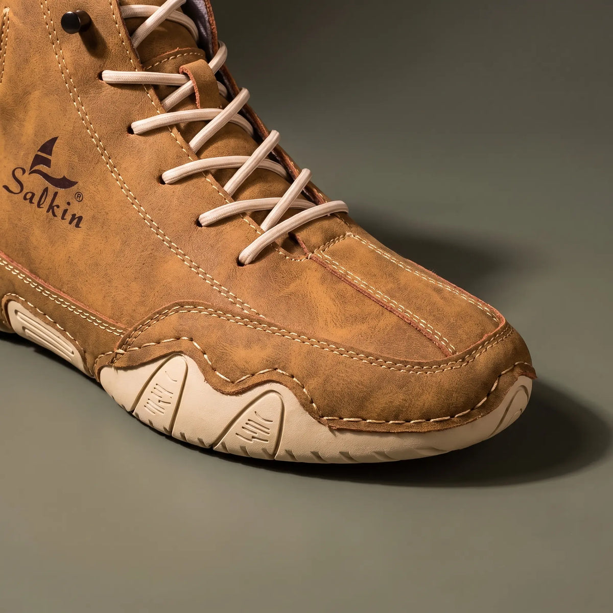 Close-up of the moc toe stitching and cream wave sole on the tan brown ankle boot