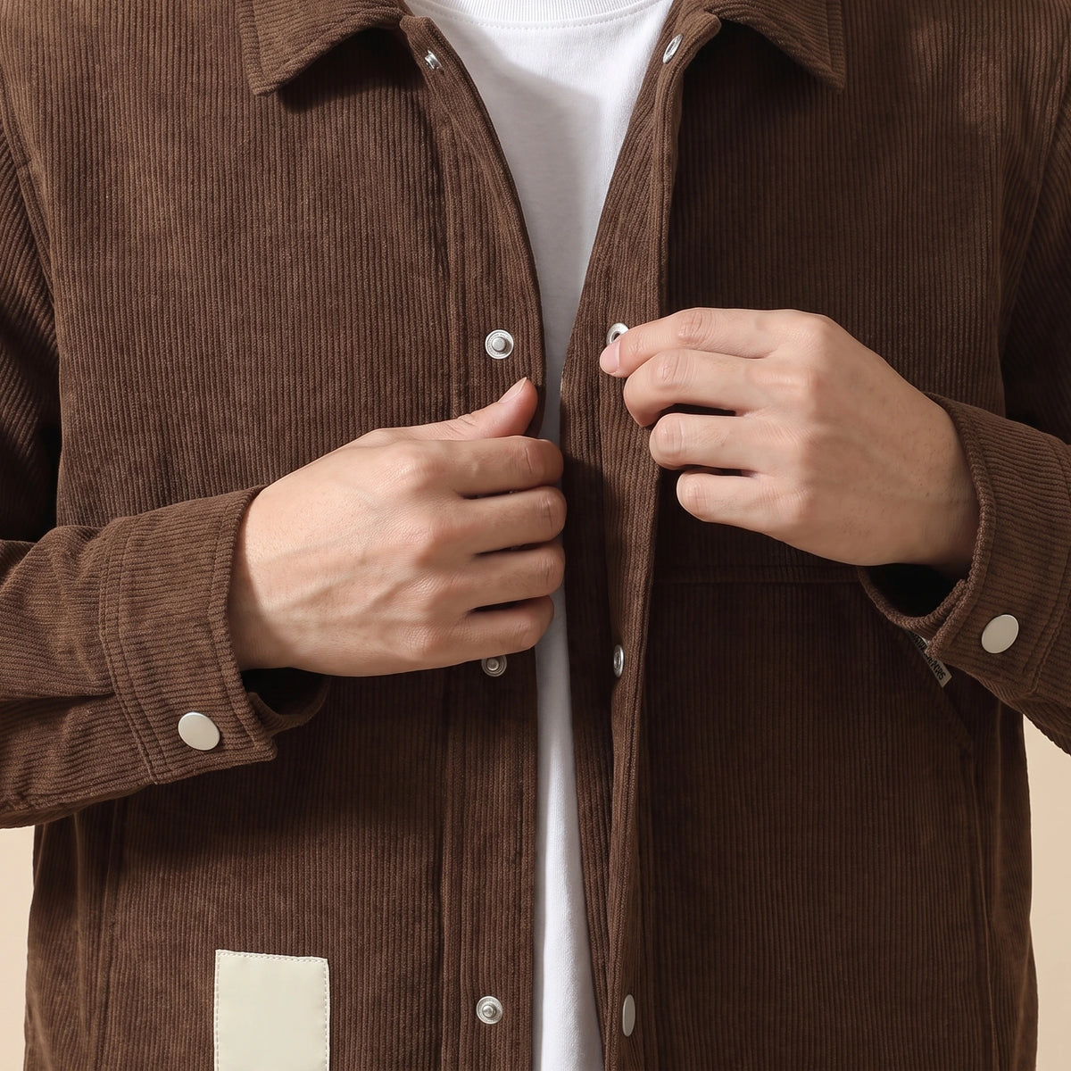 Man closing a front snap on the brown winter corduroy jacket, close chest view