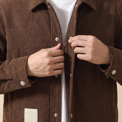Man closing a front snap on the brown winter corduroy jacket, close chest view