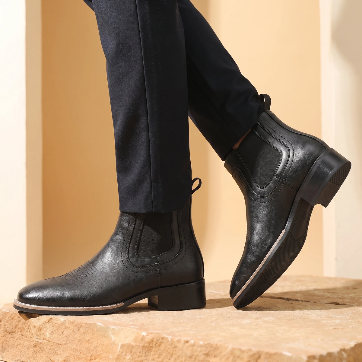 Man wearing black leather Chelsea boots mid-stride