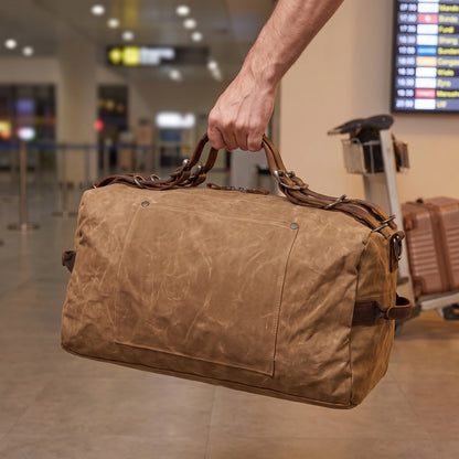 Waxed canvas duffel bag carried by the handles in an airport