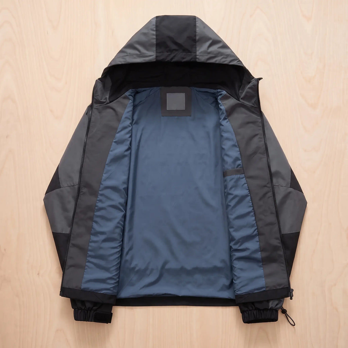 Hooded panel windbreaker laid open flat showing the smooth slate blue inner lining