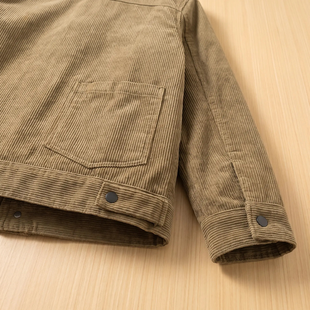 Close up of the corduroy jacket hem, patch pocket and buttoned cuff