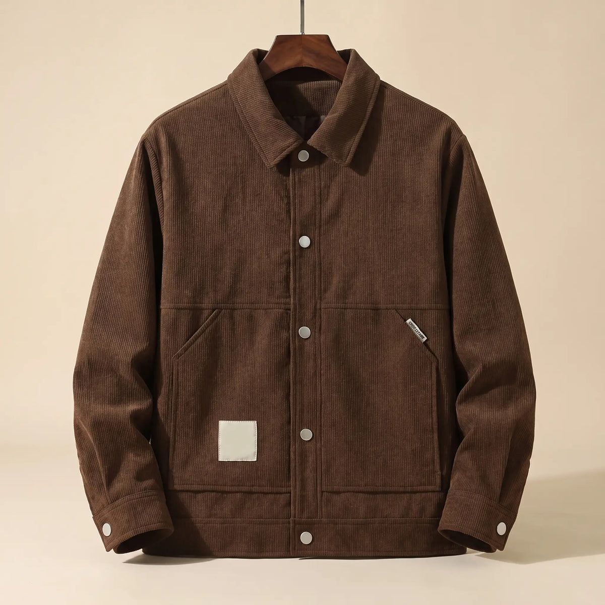 Brown padded corduroy winter jacket with snap front on a wooden hanger, front view