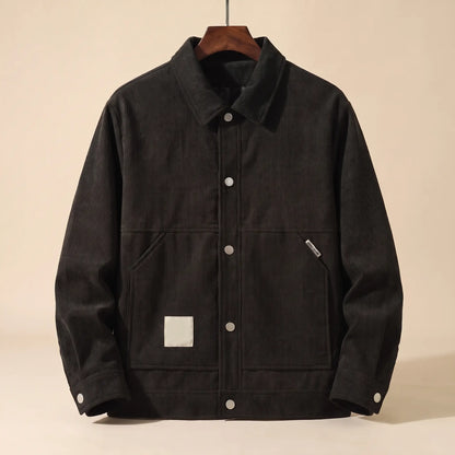 Black padded corduroy winter jacket with snap front on a wooden hanger, front view