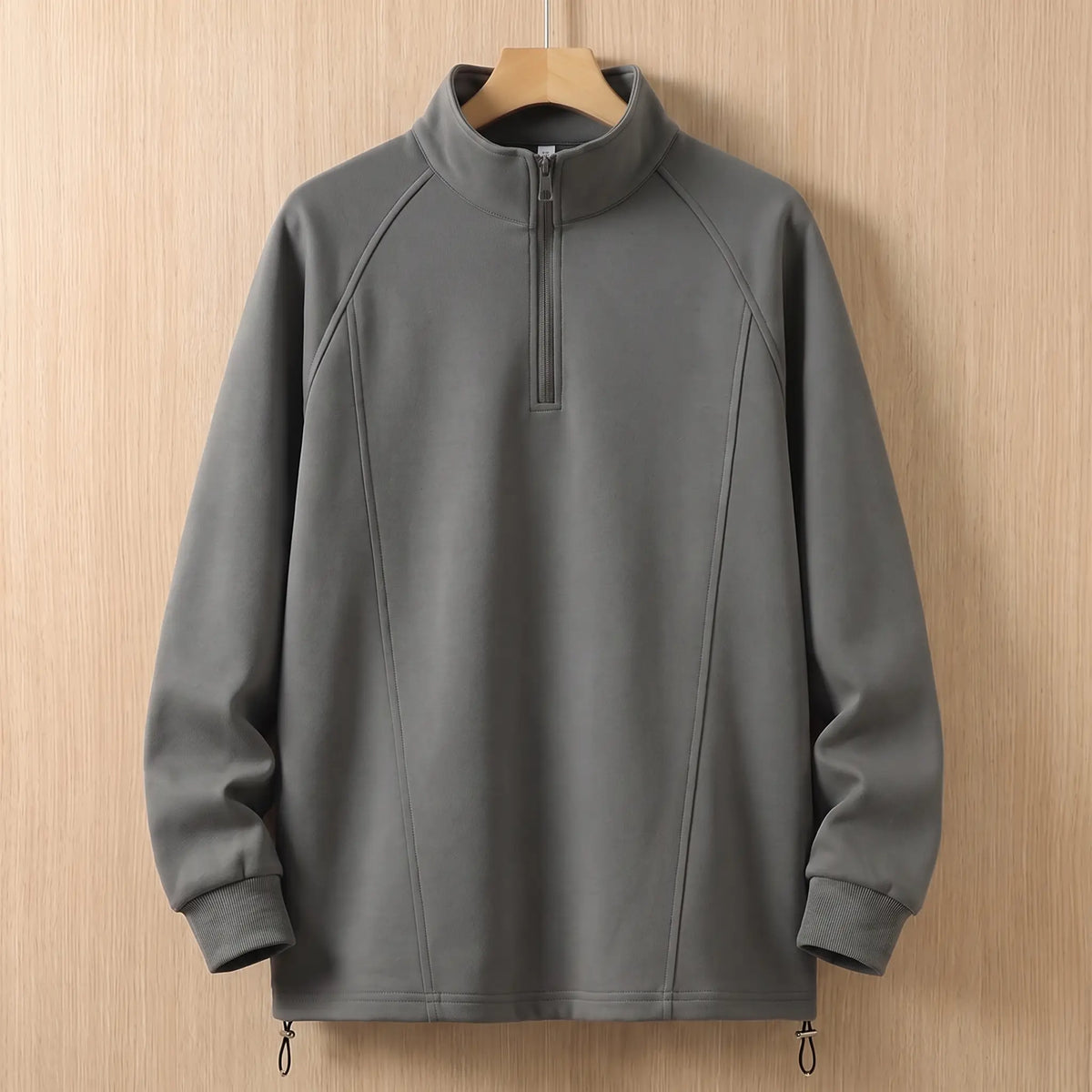 Grey oversized half zip sweatshirt with tall collar on a wooden hanger, front view