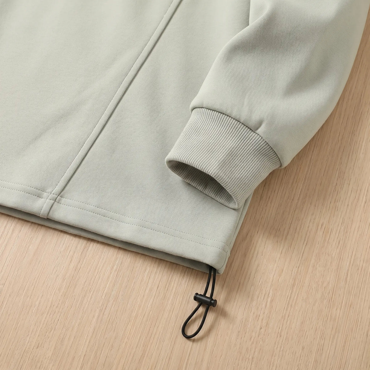 Close up of the sweatshirt hem drawcord toggle and ribbed cuff
