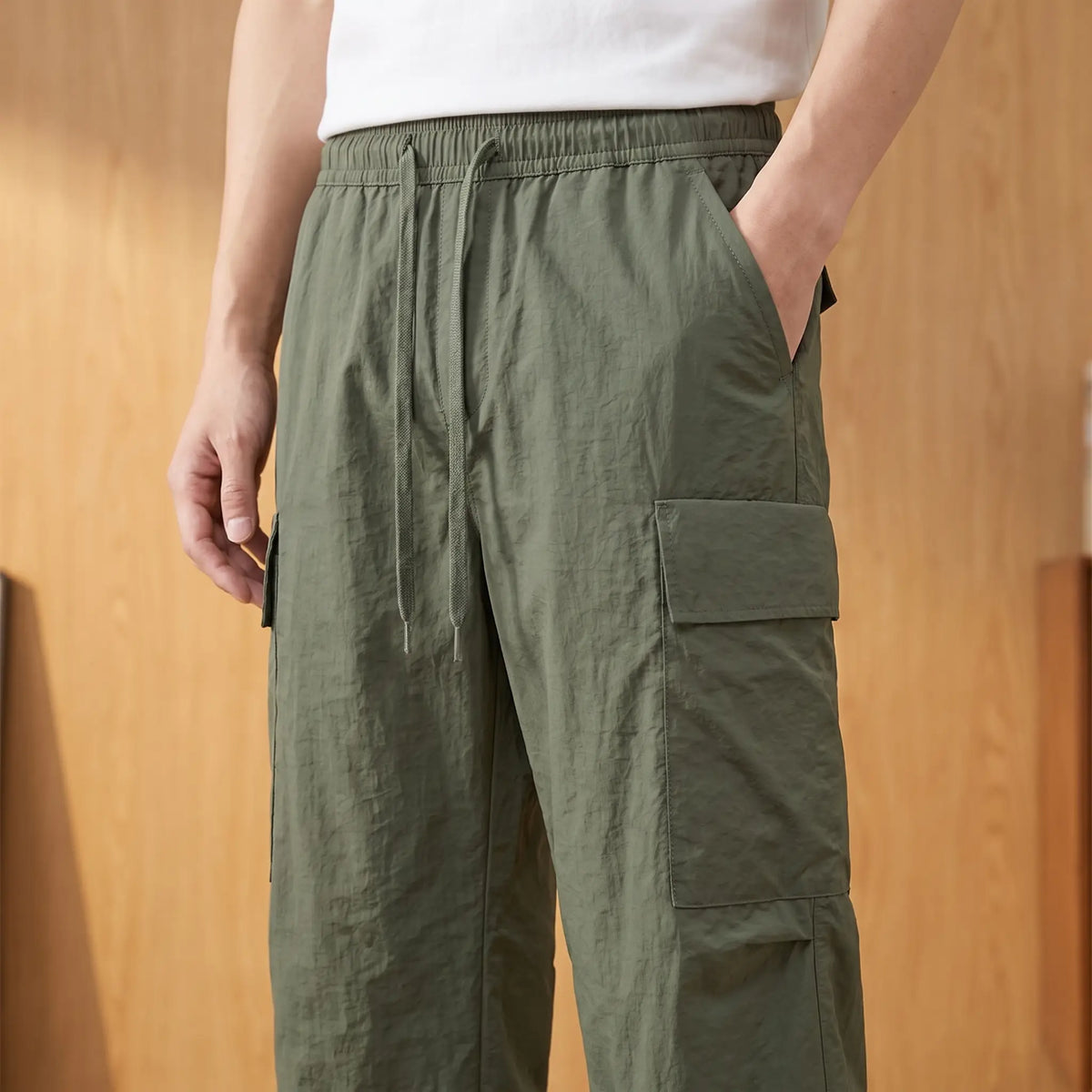 Man wearing the green trousers with one hand in the side pocket, waist level view