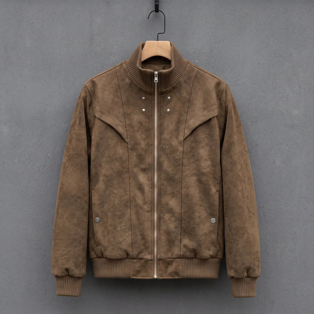 Brown suede bomber jacket with ribbed stand collar on a wooden hanger, front view