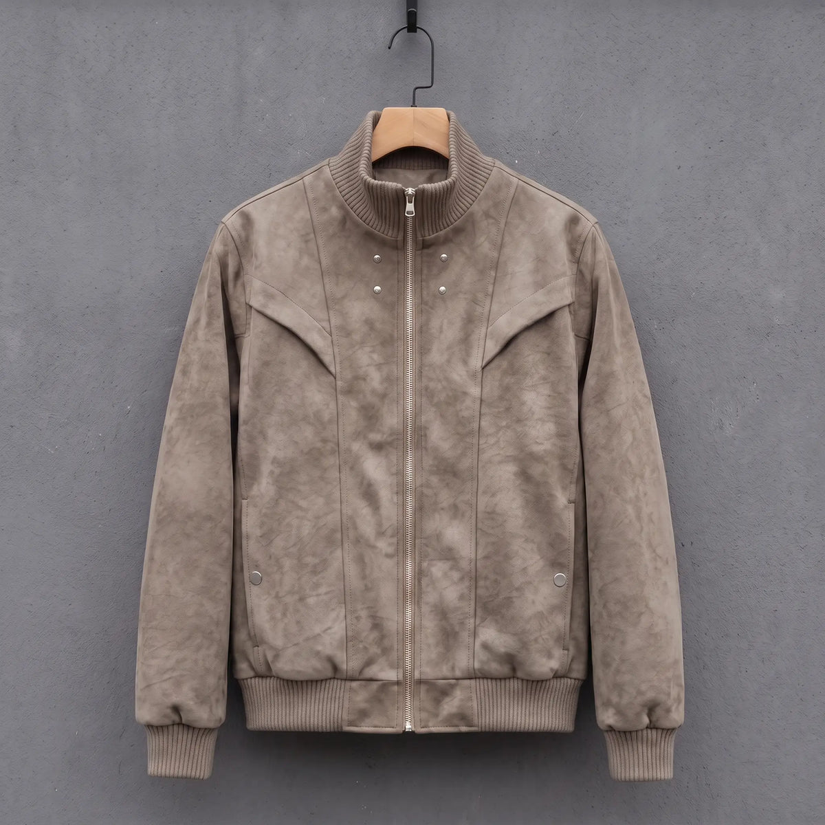Light grey suede bomber jacket with ribbed stand collar on a wooden hanger, front view