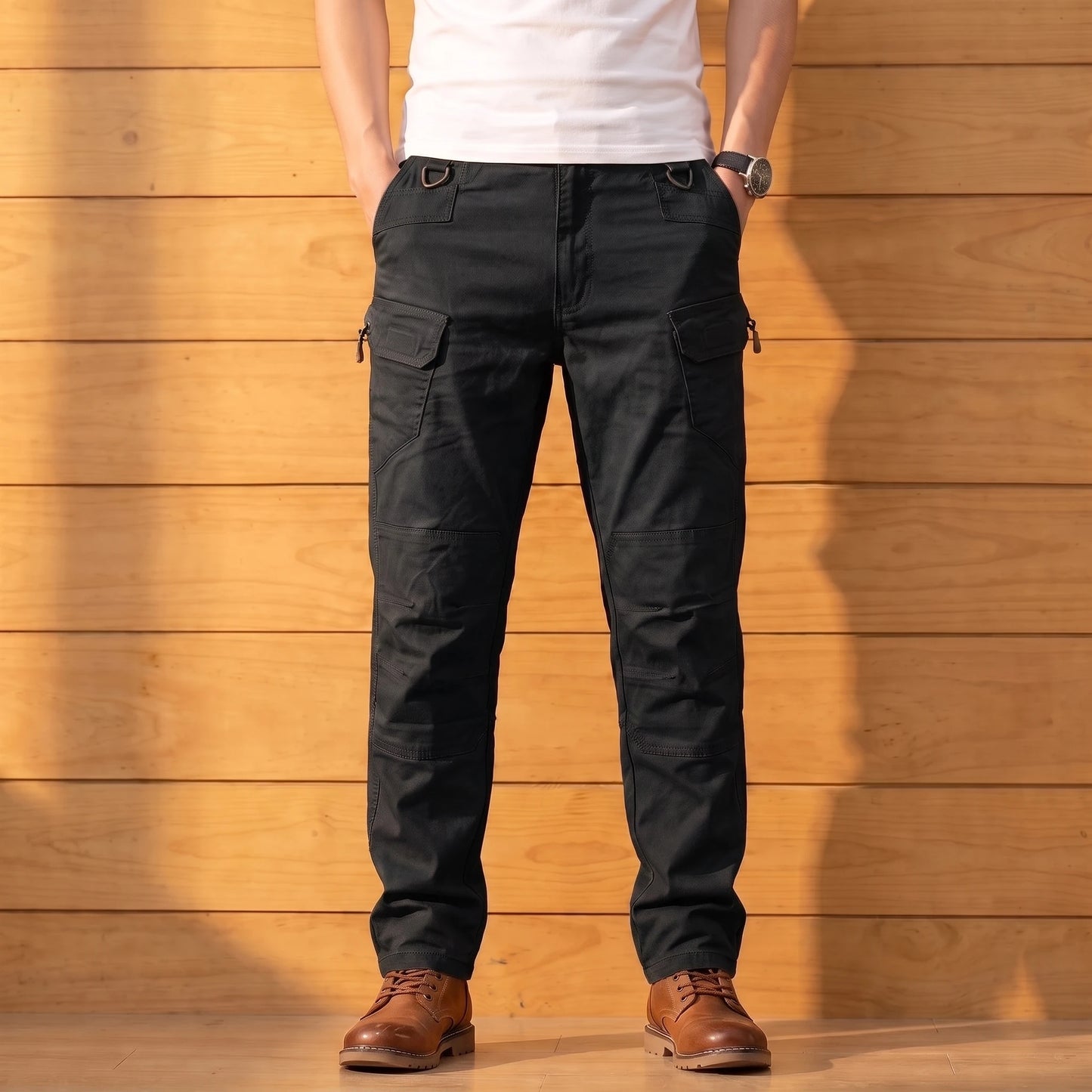 Multipocket cotton cargo pants in black, worn front view against a warm wood wall