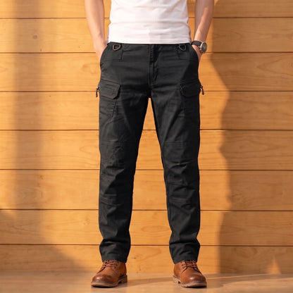 Multipocket cotton cargo pants in black, worn front view against a warm wood wall