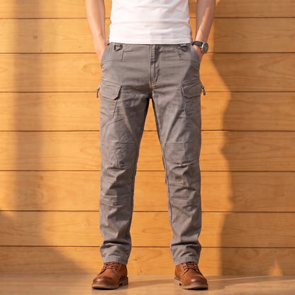 Multipocket cotton cargo pants in gray, worn front view against a warm wood wall