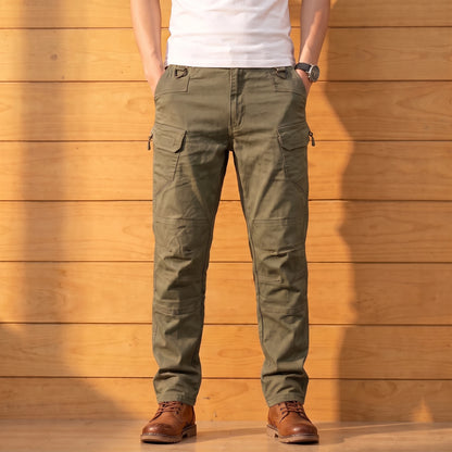 Multipocket cotton cargo pants in olive green, worn front view against a warm wood wall