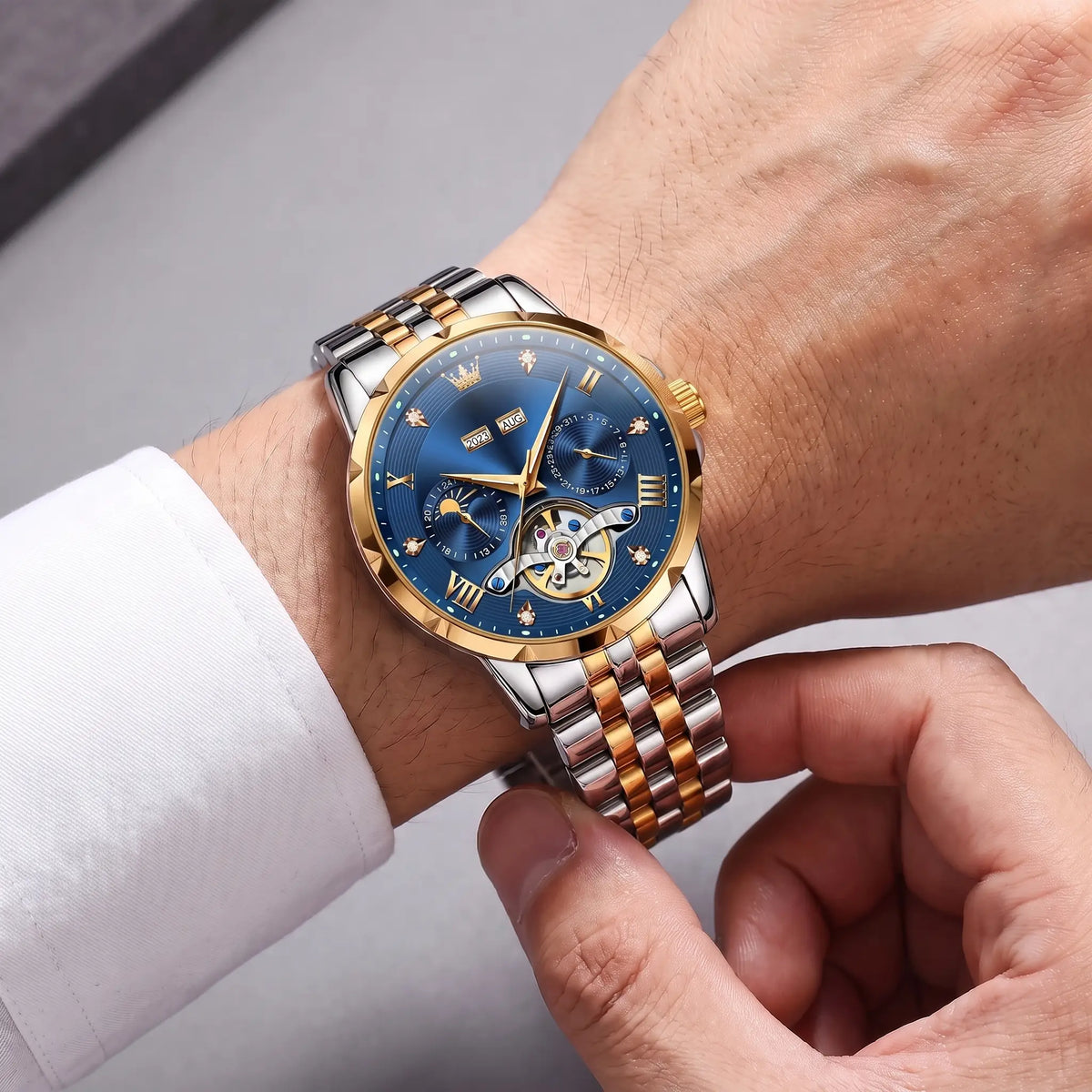 Man fastening the two tone blue dial Open Heart Watch onto his wrist over a white shirt cuff