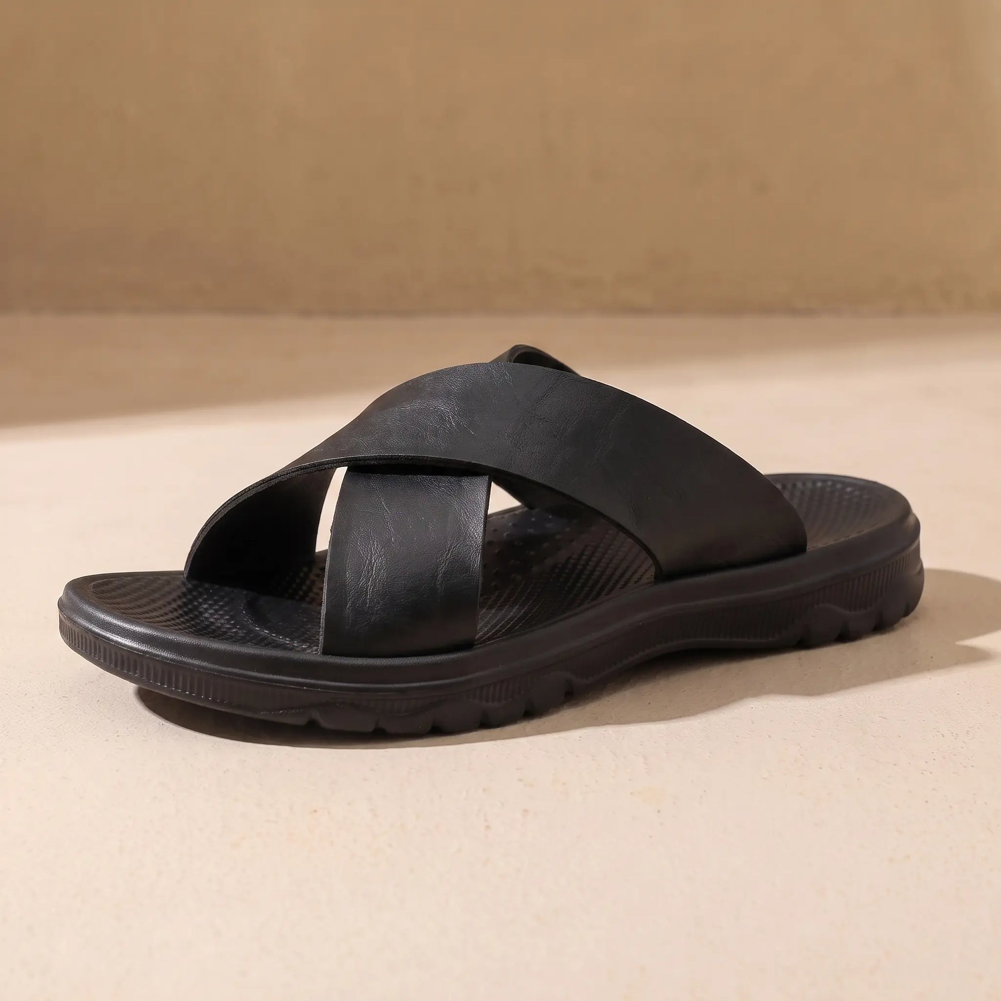 Black men's cross-strap slide sandal on sandy floor