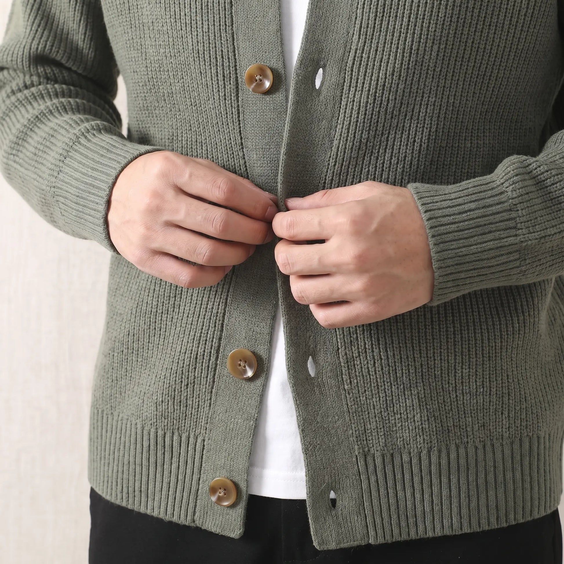 Man fastening a button on the green Rib Texture Jacket worn over a white tee
