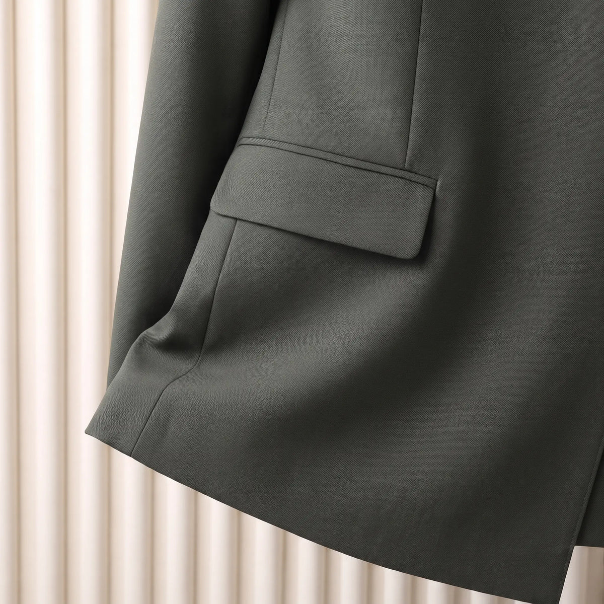Close up of the flap hip pocket and straight hem on the green Satin Lapel Blazer