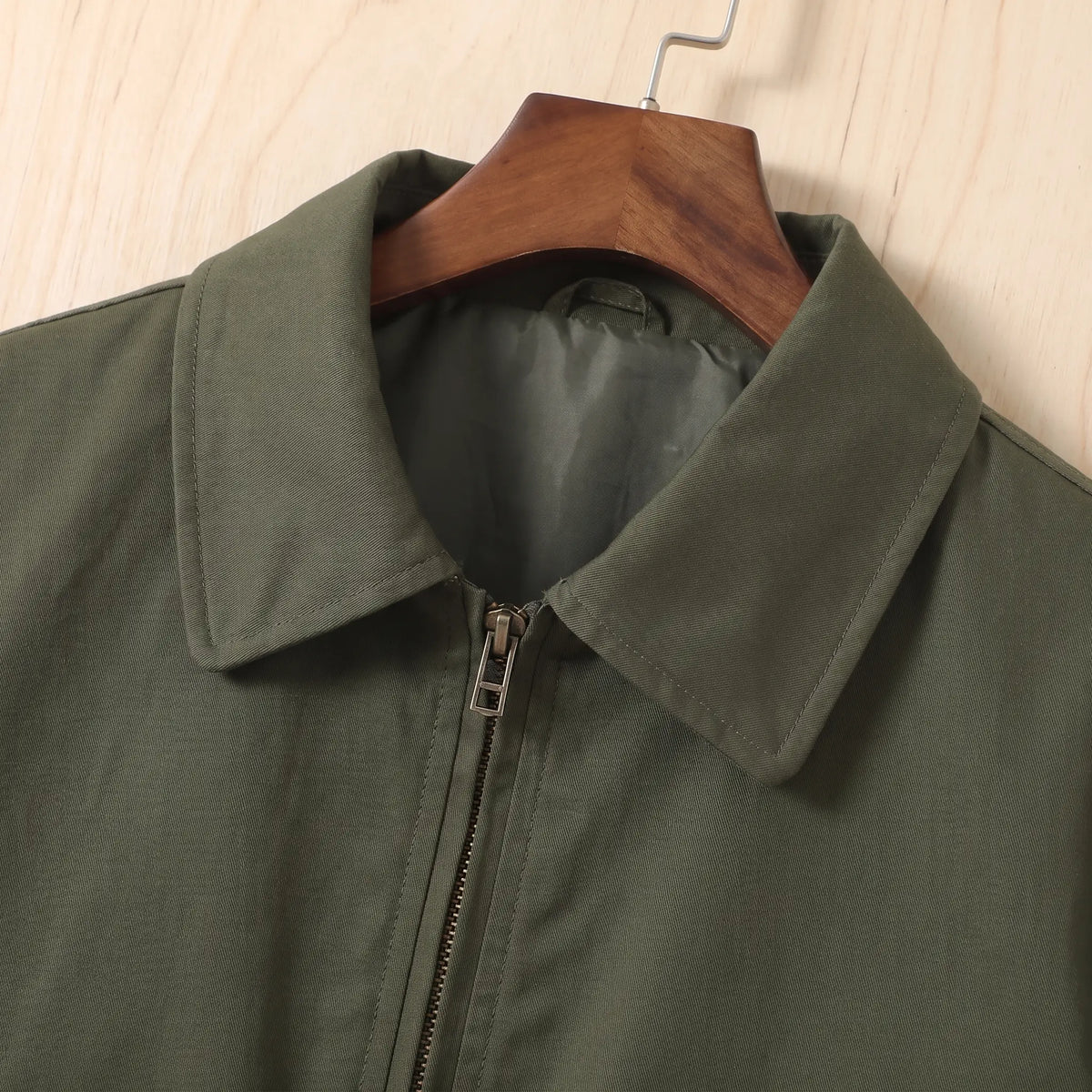 Close up of the pointed collar and metal front zip on the green Sleeve Pocket Bomber