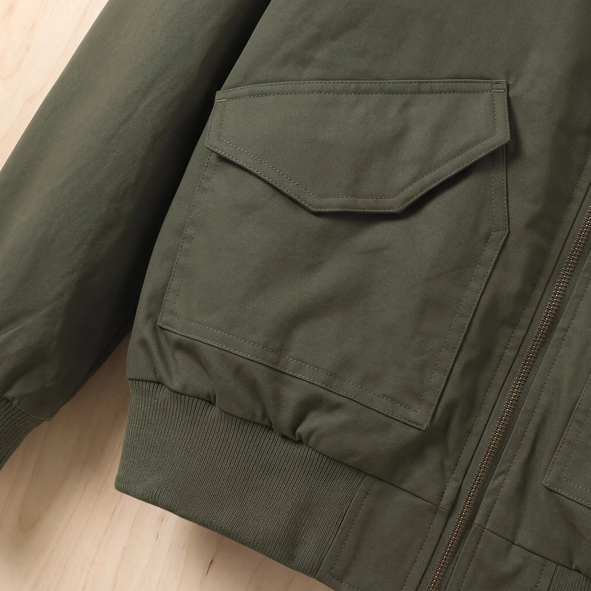 Close up of the flap hip pocket and ribbed waistband on the green Sleeve Pocket Bomber