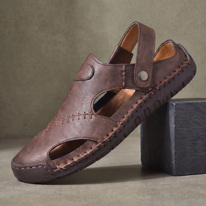 Snap Strap Sandals in dark brown, a closed toe leather fisherman sandal with cut out side panels and a metal snap instep strap, on a charcoal slate block