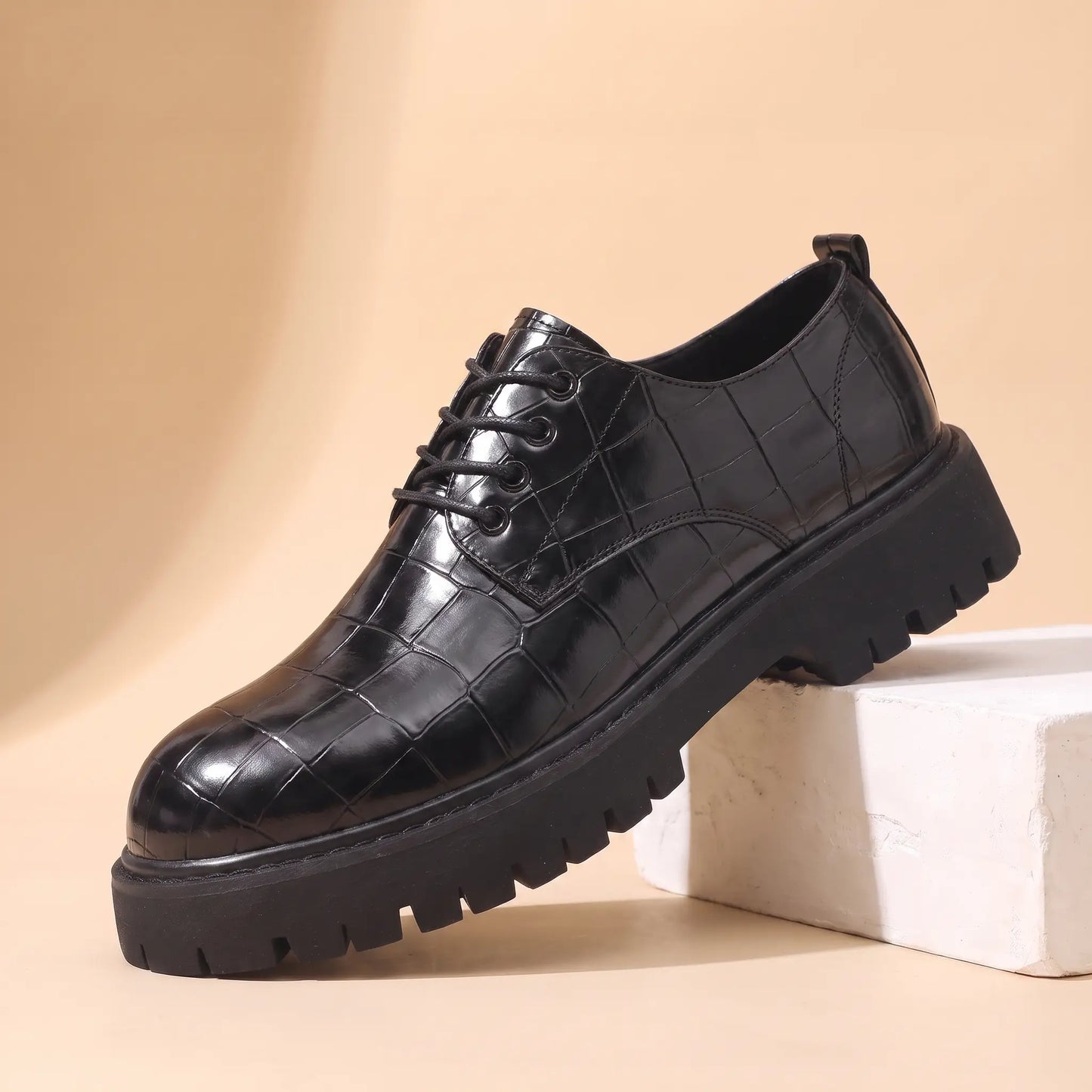 Square Scale Derby in black, a croc embossed leather derby shoe with a polished toe cap and chunky lug sole, on a plaster block