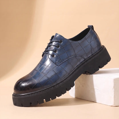 Square Scale Derby in blue, a croc embossed leather derby shoe with a burnished toe cap and chunky lug sole, on a plaster block
