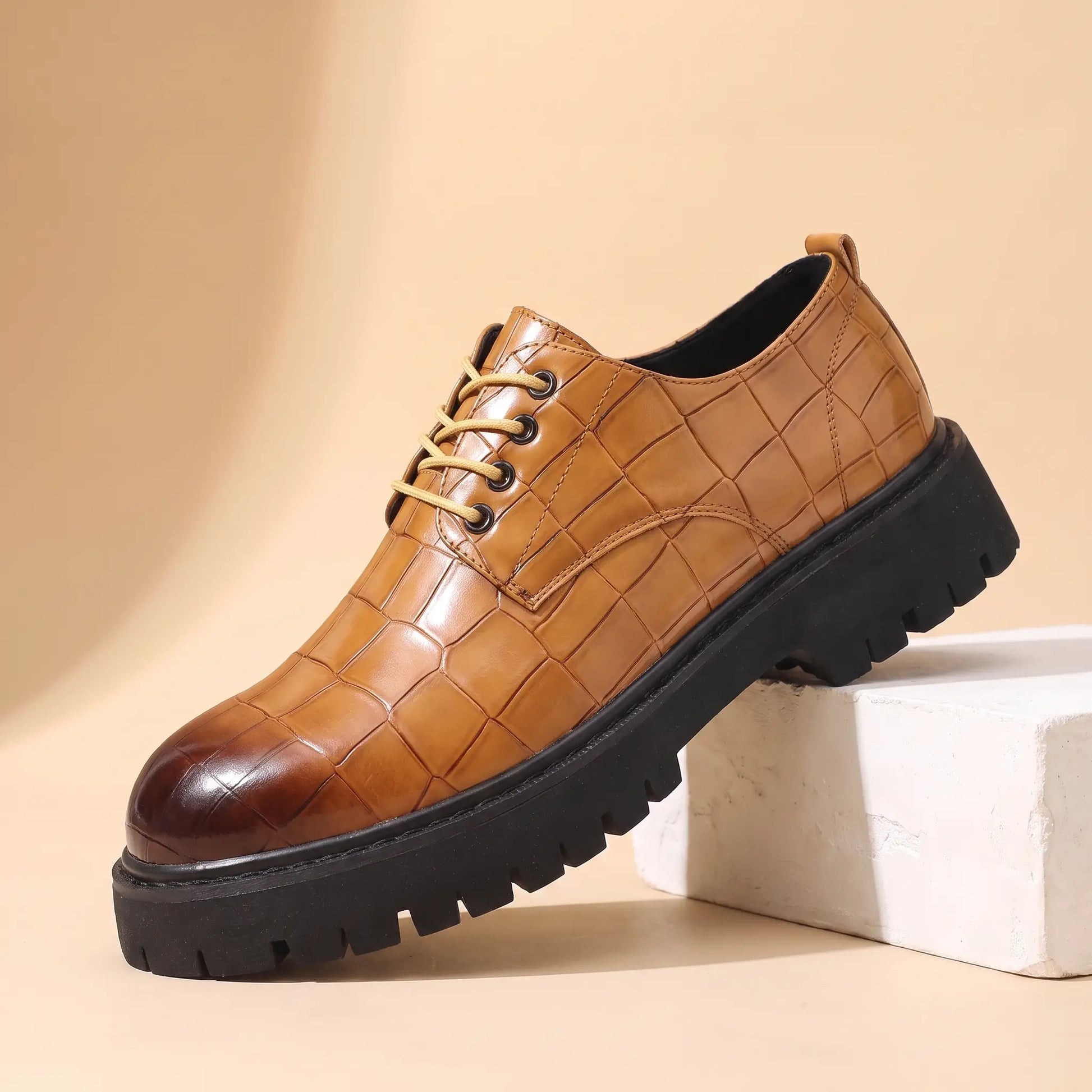 Square Scale Derby in tan, a croc embossed leather derby shoe with a burnished toe cap and chunky lug sole, on a plaster block