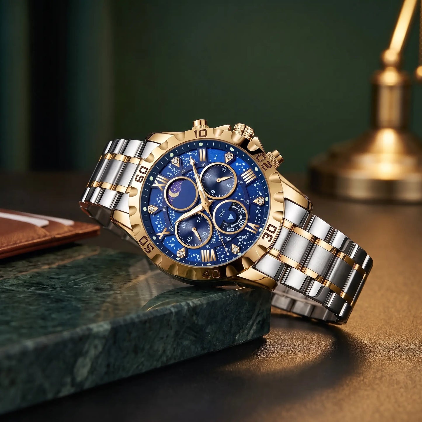 Starry Dial Watch with gold case, blue star pattern dial and two tone steel band, resting on a green marble ledge