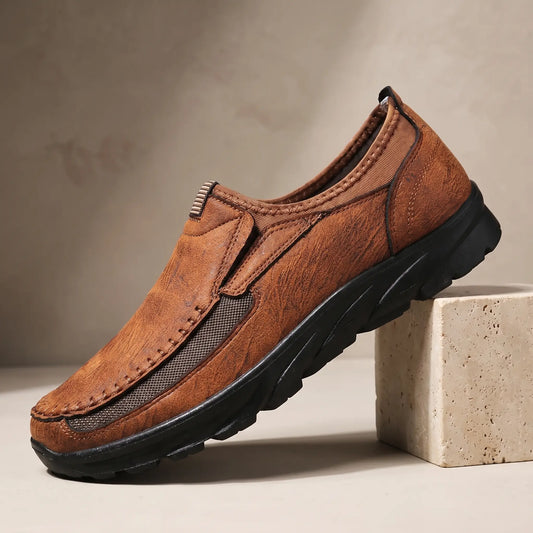 Stitched Apron Loafers in light brown, a slip on moccasin loafer with elastic side panels and a chunky black bottom, on a travertine display block