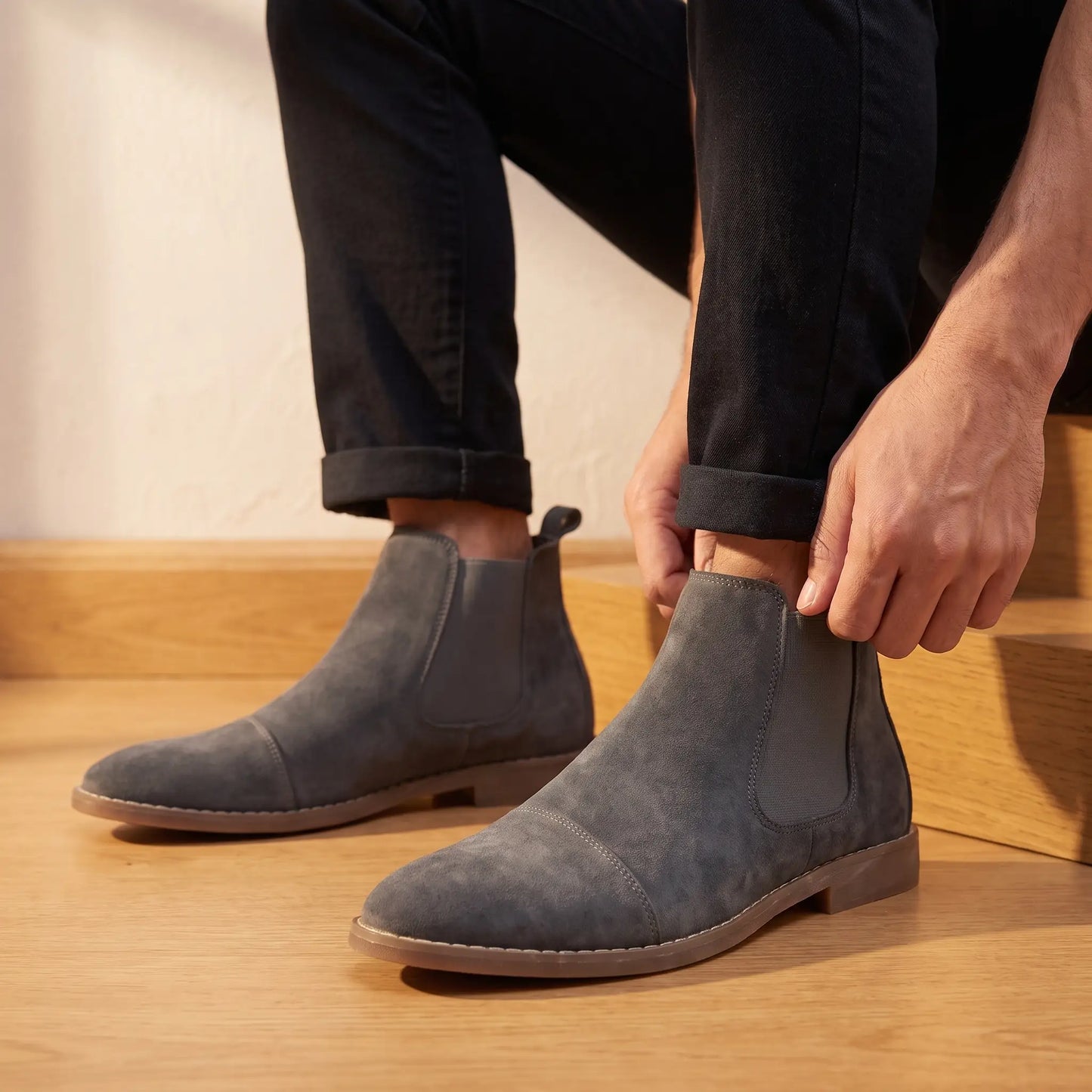 Man seated wearing the Stretch Panel Boots, settling the elastic side panel at the ankle