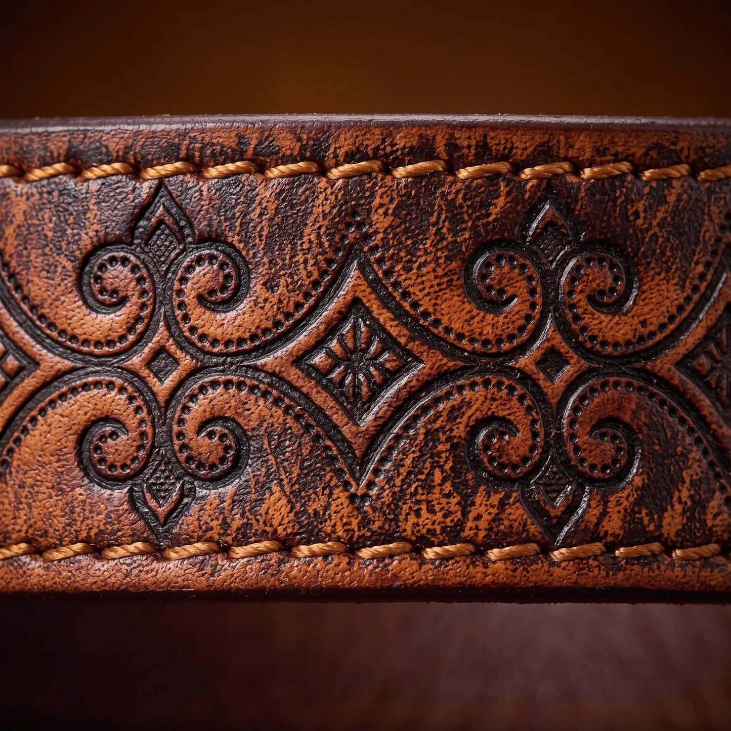 Macro close up of the carved scroll tooling and edge stitching on the Tooled Pattern Belt