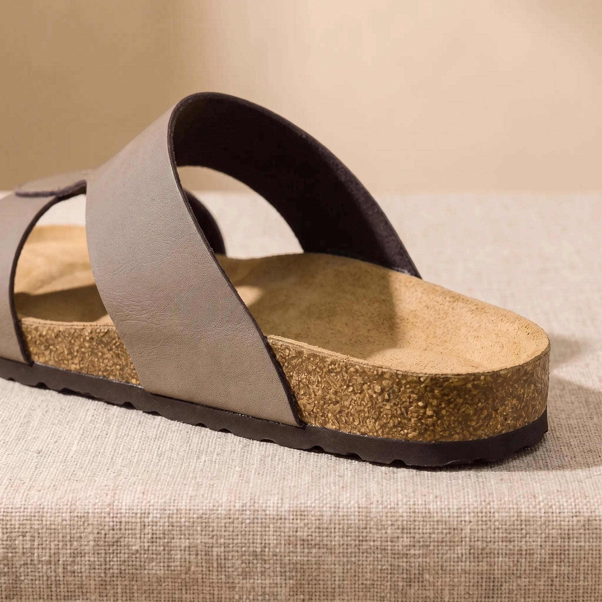 Close up of the contoured heel cup, layered cork sidewall and treaded bottom on the taupe Two Strap Slides