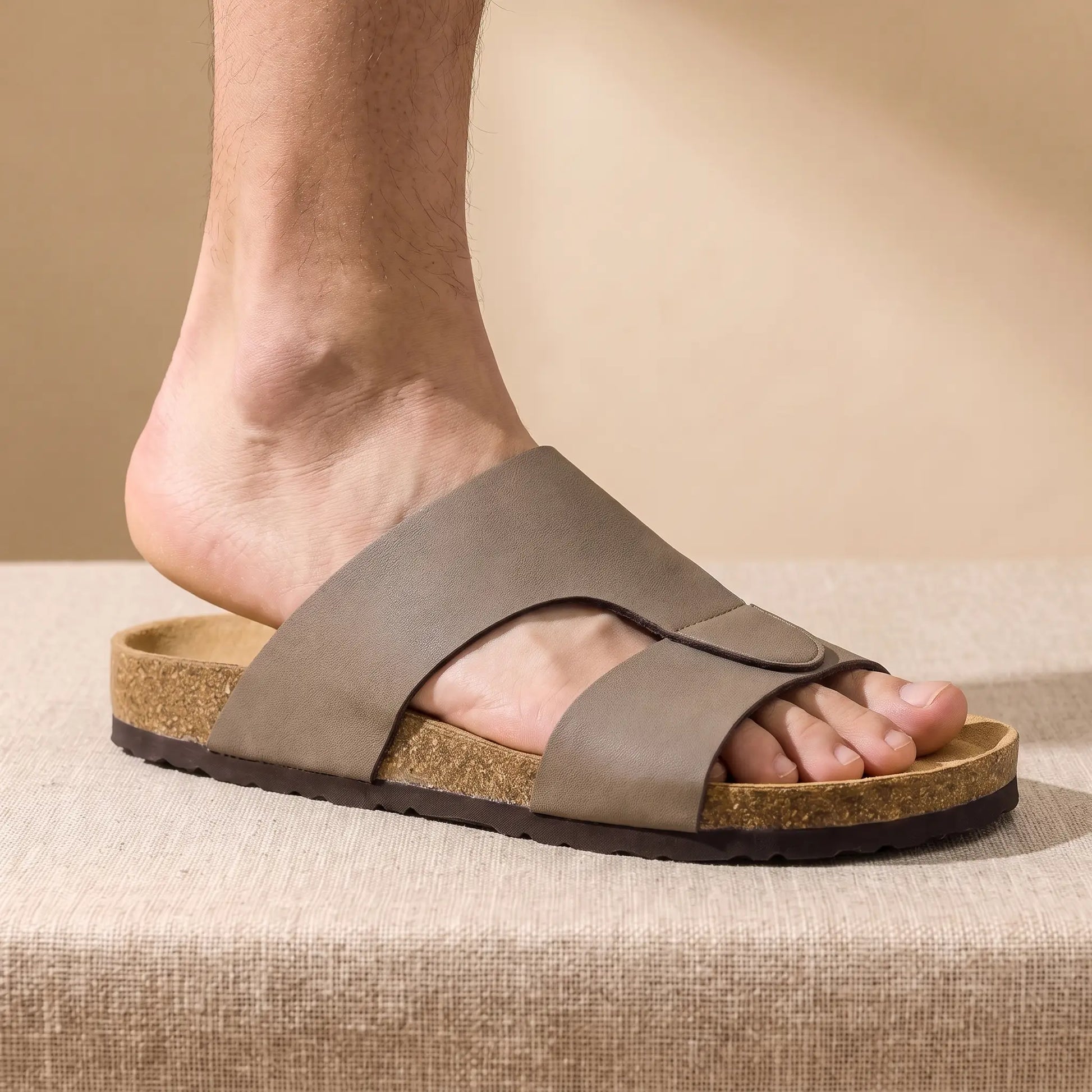 Man sliding his foot into the taupe Two Strap Slides at floor level