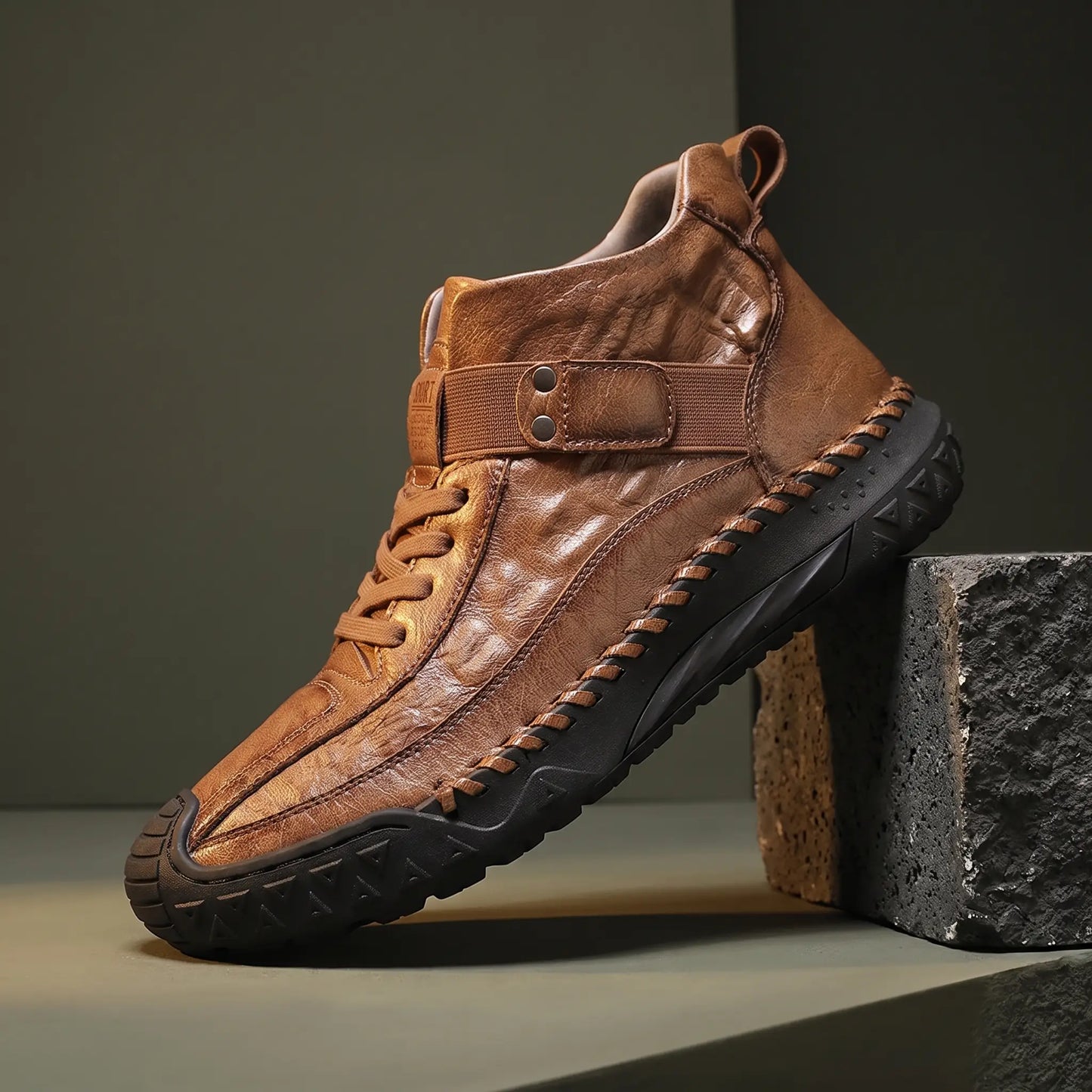 Light brown high top boot with croc embossed panel on a basalt block